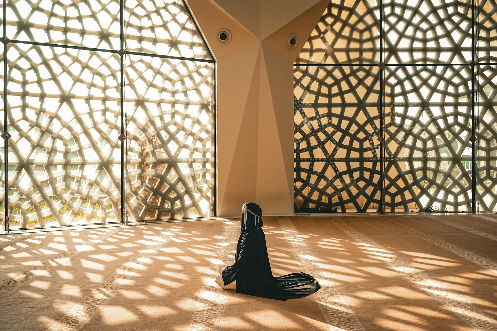 woman praying in mosque with openwork windows