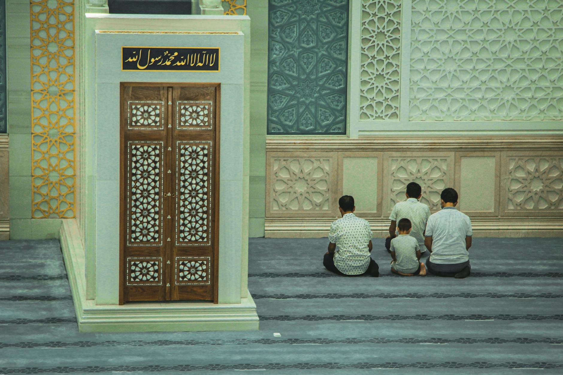 people sitting on concrete floor in front of a wall with intricate desings